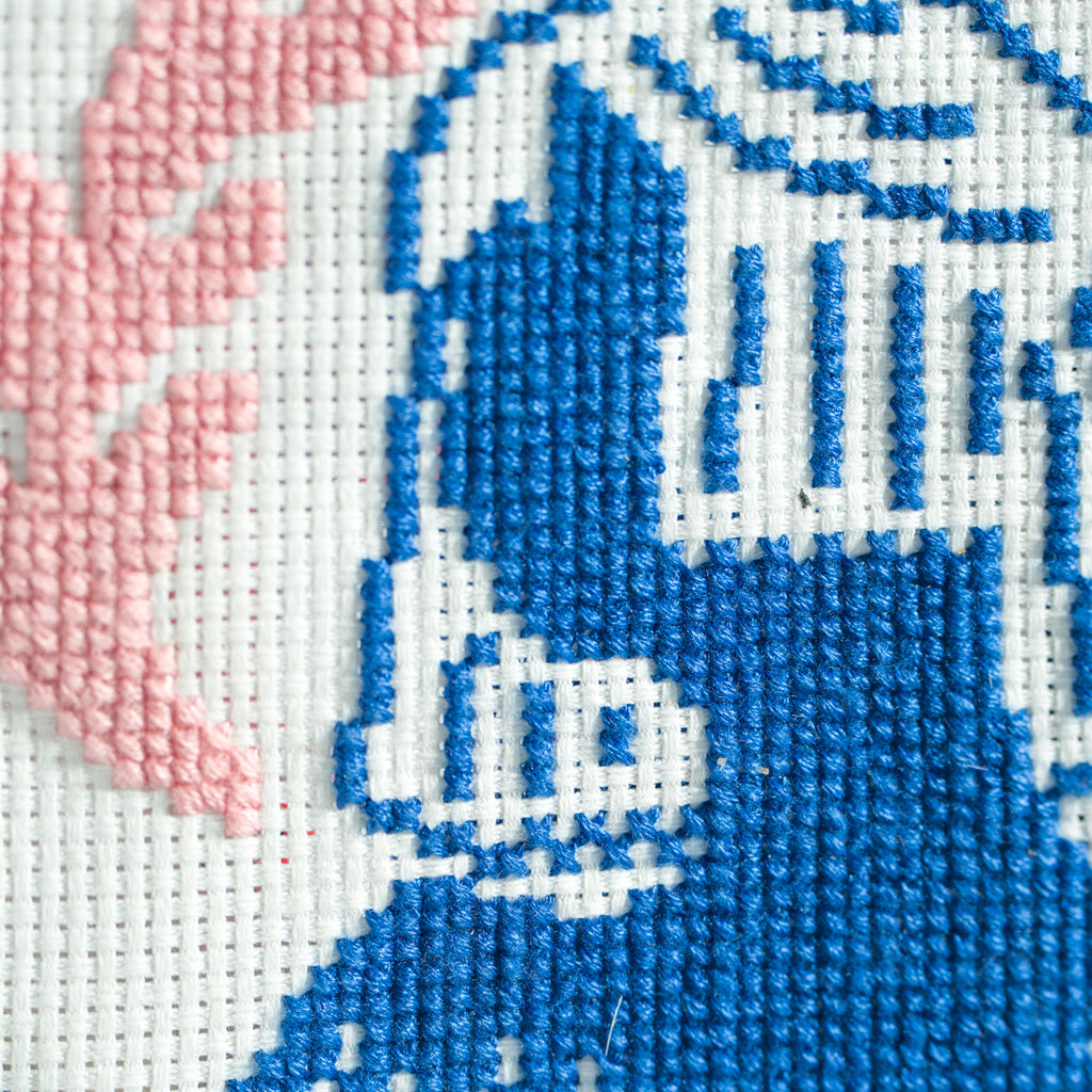 close up of cross stitch silhouette of woman with pink detailing 