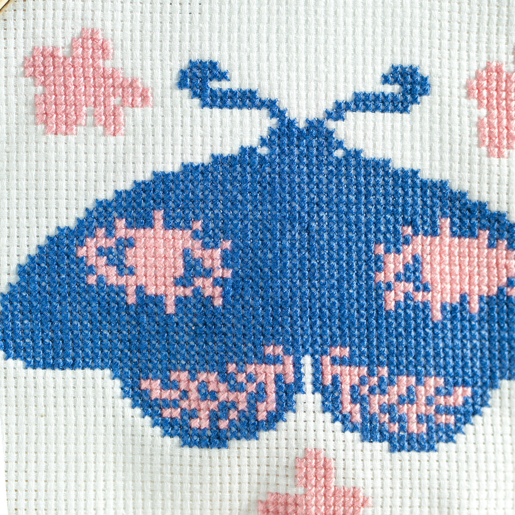 Close up of Moth with eyes surrounded by flowers on finished cross stitch kit